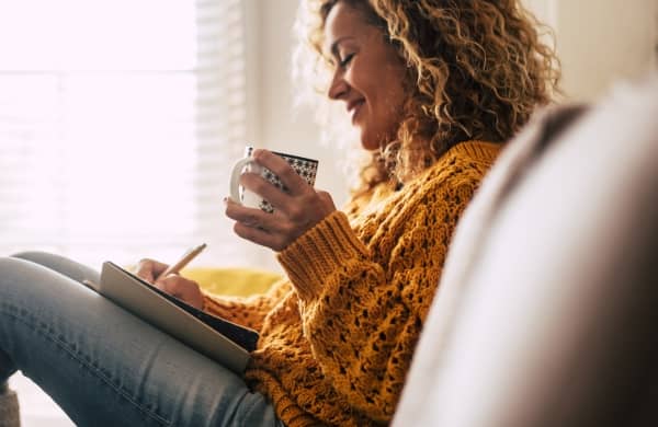 Woman writing gratitude journal entry.